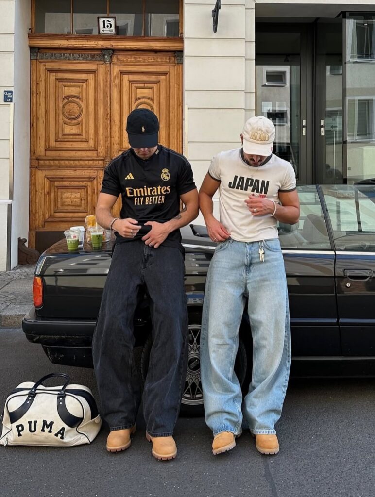 Two men standing by a car wearing baggy jeans and tan Timberland boots.