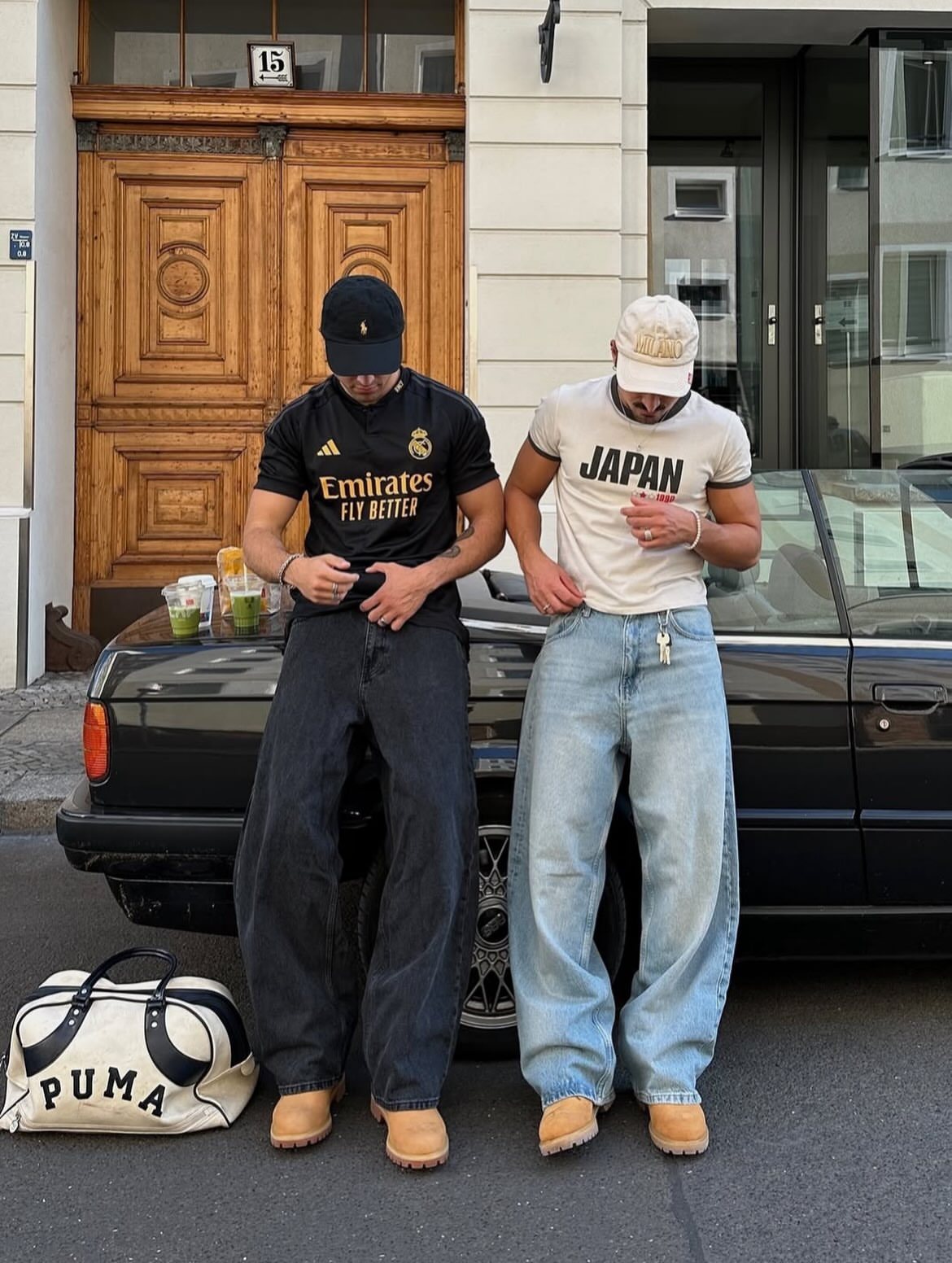 Two men standing by a car wearing baggy jeans and tan Timberland boots.