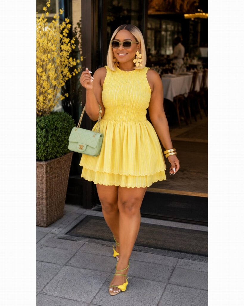 Woman in a bright yellow sleeveless mini dress and yellow strappy sandals walking outdoors.